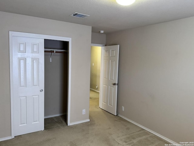 unfurnished bedroom with light colored carpet and a closet