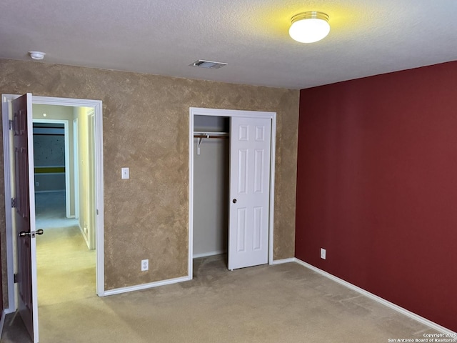 unfurnished bedroom with light carpet, a closet, and a textured ceiling