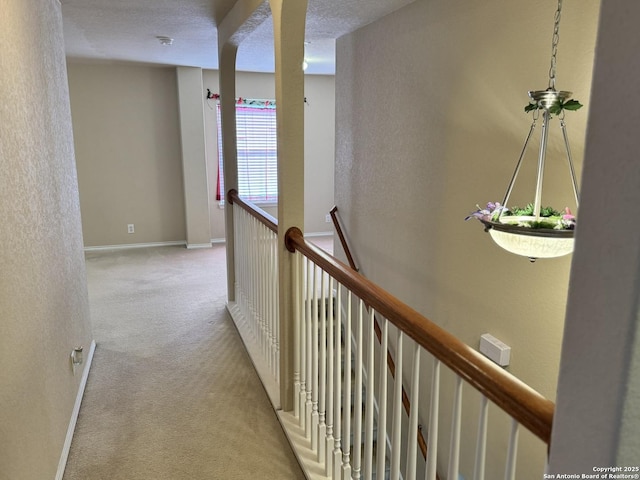 hall featuring light colored carpet and a textured ceiling