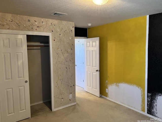 unfurnished bedroom with a textured ceiling, light carpet, and a closet