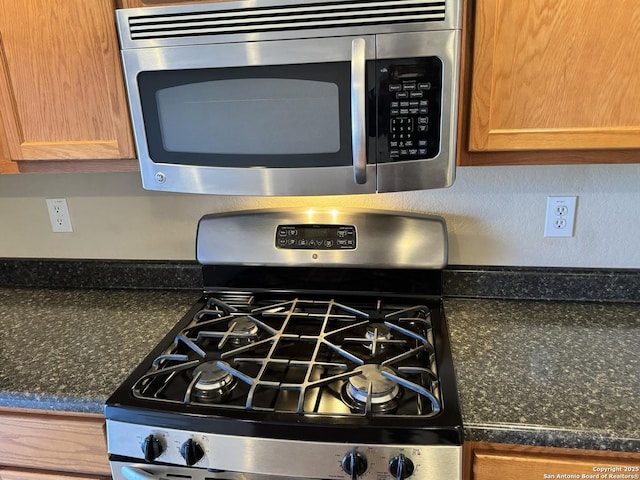 interior details featuring appliances with stainless steel finishes and dark stone counters