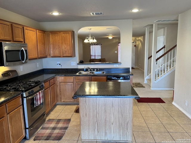 kitchen featuring sink, a kitchen island, a notable chandelier, light tile patterned floors, and appliances with stainless steel finishes