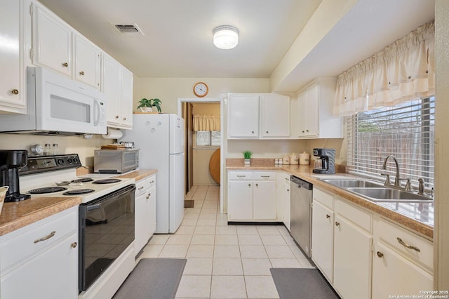 kitchen with light tile patterned floors, white cabinetry, sink, and white appliances