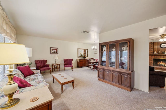 living room with light carpet, a brick fireplace, and a notable chandelier