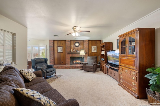 living room with ceiling fan, light carpet, a brick fireplace, and wooden walls