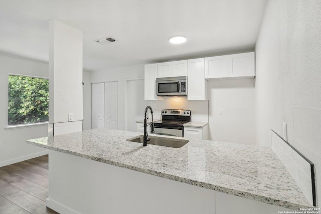 kitchen with appliances with stainless steel finishes, tasteful backsplash, light stone counters, sink, and white cabinetry