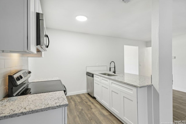 kitchen featuring light stone countertops, stainless steel appliances, sink, hardwood / wood-style floors, and white cabinetry