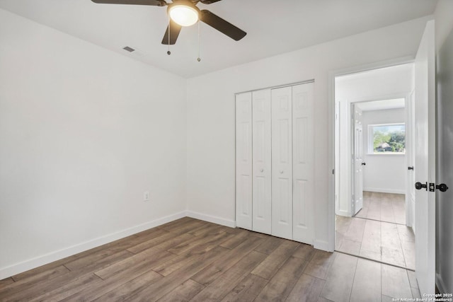 unfurnished bedroom featuring a closet, hardwood / wood-style flooring, and ceiling fan