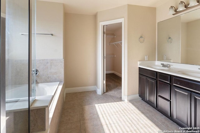 bathroom with tile patterned floors, tiled tub, and vanity