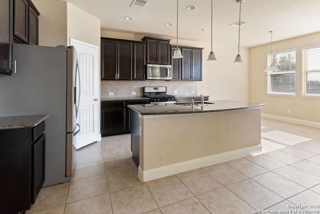 kitchen featuring pendant lighting, stainless steel appliances, light tile patterned floors, and a kitchen island with sink