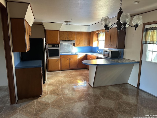 kitchen featuring oven, sink, fridge, decorative light fixtures, and kitchen peninsula