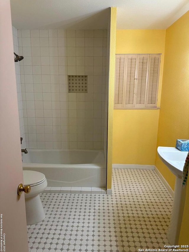 bathroom with tile patterned flooring, tiled shower / bath combo, and toilet