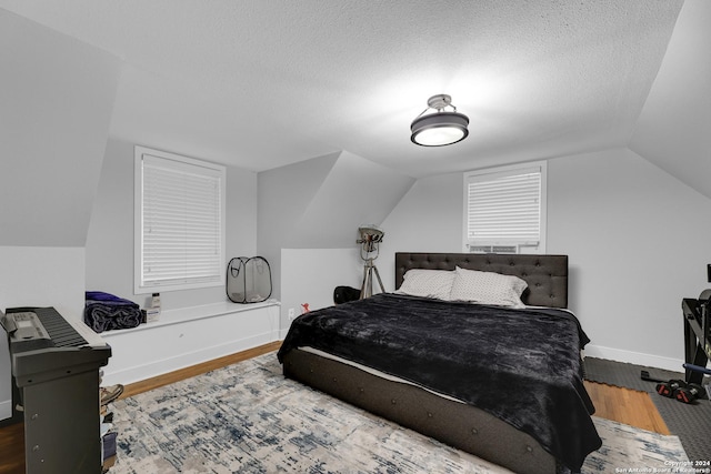 bedroom featuring lofted ceiling, a textured ceiling, and hardwood / wood-style flooring