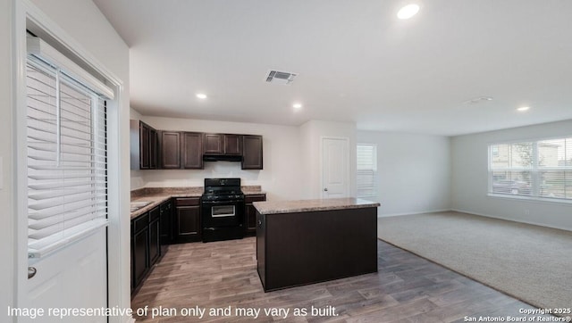 kitchen with hardwood / wood-style flooring, a kitchen island, dark brown cabinetry, and black range with gas cooktop