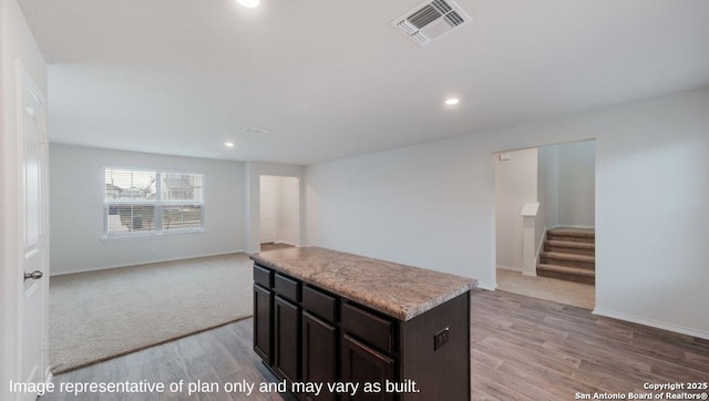 kitchen featuring a center island, light wood finished floors, light countertops, visible vents, and open floor plan