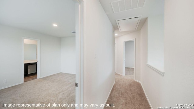 corridor with baseboards, carpet, visible vents, and attic access