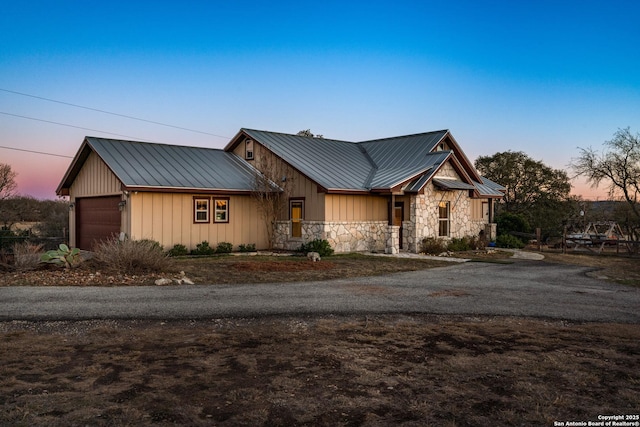 view of front of home with stone siding, board and batten siding, and metal roof