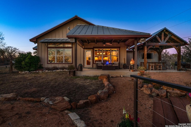 back house at dusk featuring an outdoor living space, a gazebo, ceiling fan, a bar, and a patio