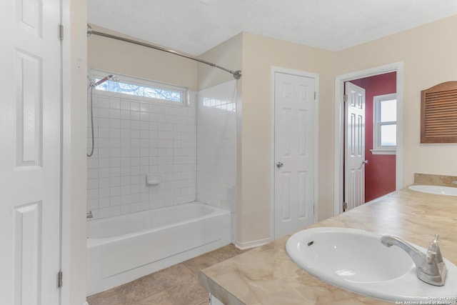 bathroom with tile patterned flooring, tiled shower / bath, vanity, and a textured ceiling