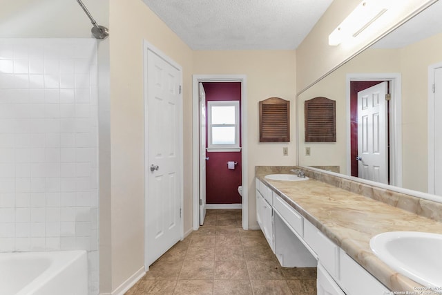 full bathroom with tile patterned flooring, tiled shower / bath combo, vanity, a textured ceiling, and toilet