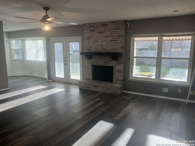 unfurnished living room with a textured ceiling, a brick fireplace, french doors, ceiling fan, and dark hardwood / wood-style floors