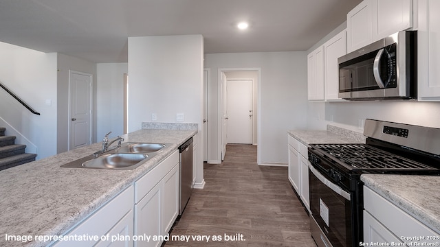 kitchen with white cabinets, appliances with stainless steel finishes, hardwood / wood-style flooring, and sink