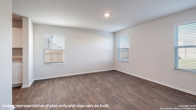 empty room with a healthy amount of sunlight and dark wood-type flooring