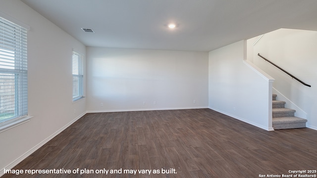 spare room featuring a healthy amount of sunlight and dark wood-type flooring