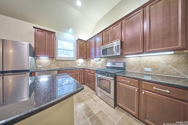 kitchen featuring dark stone counters, stainless steel appliances, vaulted ceiling, sink, and light tile patterned floors