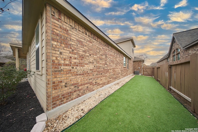 property exterior at dusk with a lawn and central air condition unit