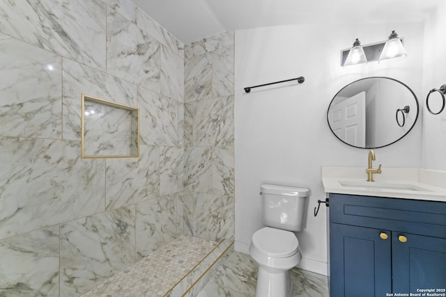 bathroom featuring a tile shower, vanity, and toilet