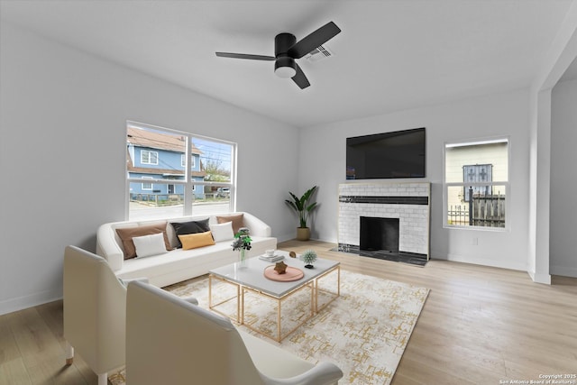 living room with ceiling fan, light wood-type flooring, and a brick fireplace