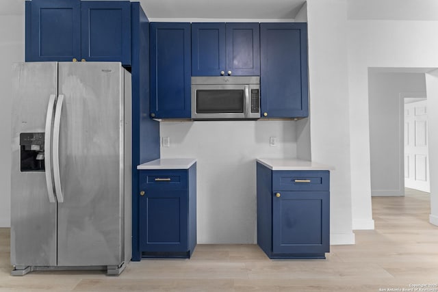 kitchen with light hardwood / wood-style floors, blue cabinetry, and appliances with stainless steel finishes