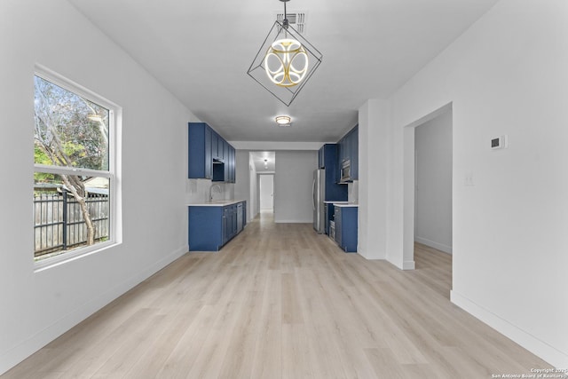 unfurnished living room with a chandelier, light hardwood / wood-style floors, and sink