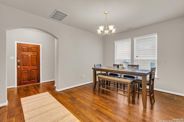 dining space with dark hardwood / wood-style flooring and a notable chandelier