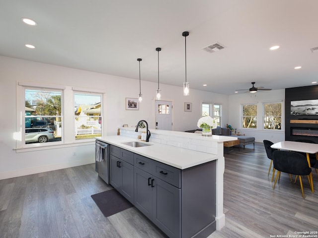 kitchen with sink, ceiling fan, dishwasher, and a kitchen island with sink