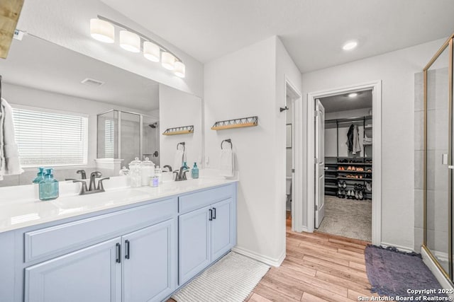 bathroom featuring a shower with door and vanity