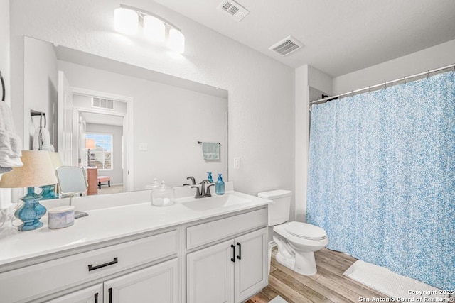 bathroom with wood-type flooring, vanity, toilet, and curtained shower