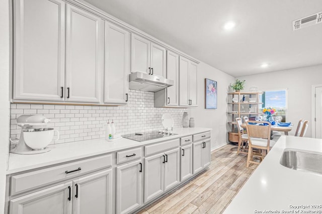 kitchen featuring decorative backsplash, light hardwood / wood-style floors, and black electric cooktop