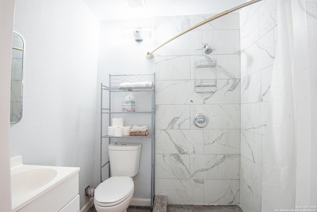 bathroom featuring toilet, vanity, and tiled shower