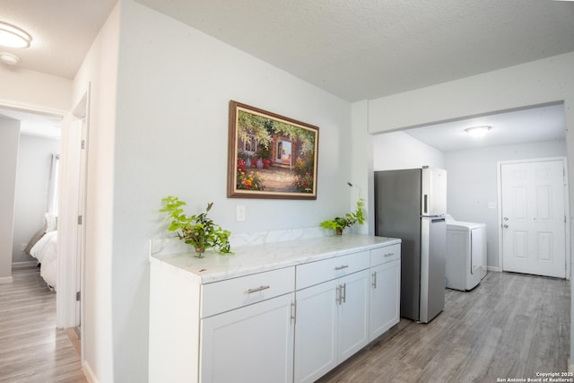 interior space featuring a textured ceiling, washer / clothes dryer, and light hardwood / wood-style flooring