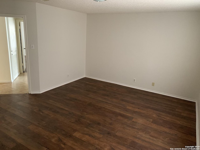 unfurnished room featuring a textured ceiling and dark wood-type flooring