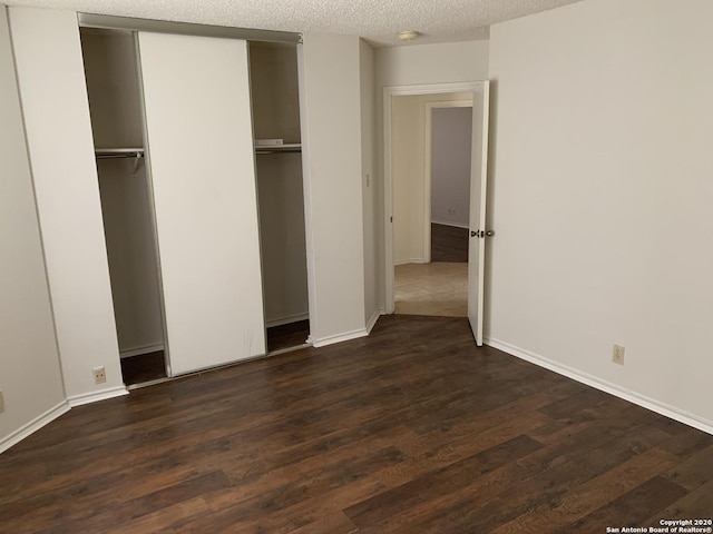 unfurnished bedroom with a closet, dark wood-type flooring, and a textured ceiling