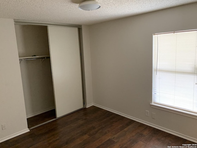 unfurnished bedroom featuring dark hardwood / wood-style floors, a textured ceiling, and a closet