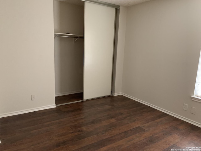 unfurnished bedroom with dark hardwood / wood-style floors and a closet