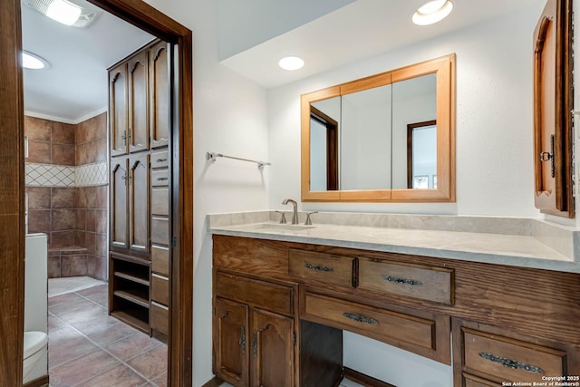 bathroom featuring tile patterned flooring, a tile shower, vanity, and toilet