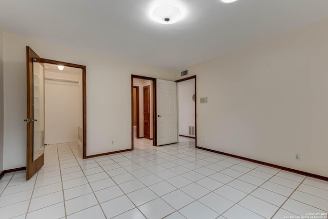 unfurnished bedroom with a spacious closet, a closet, and light tile patterned flooring