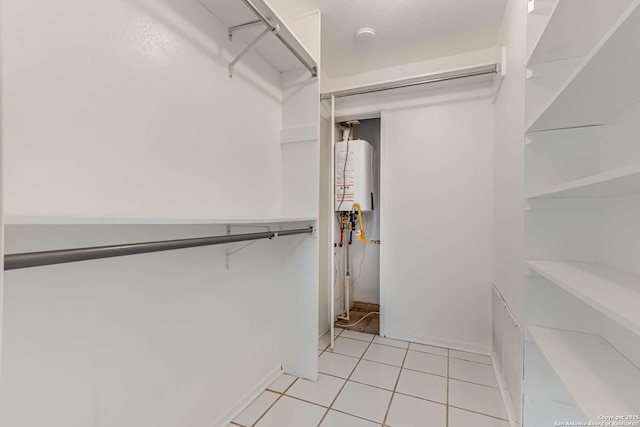 spacious closet featuring water heater and light tile patterned floors