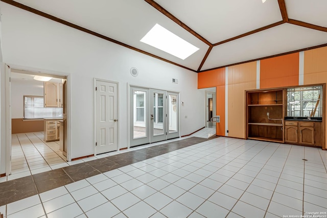 unfurnished living room with light tile patterned flooring, high vaulted ceiling, and a skylight