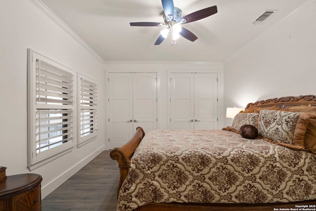 bedroom with multiple closets, ceiling fan, dark wood-type flooring, and ornamental molding